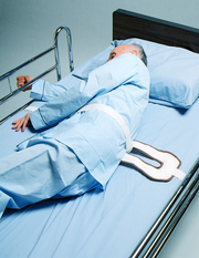 Person lying in a hospital bed with blue sheets and pillow