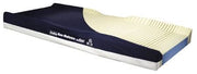 A side-view product shot of a memory foam mattress topper on a solid white background. The top layer is dark navy blue with white text reading 'Memory Foam Mattress Topper' and a circular 'B' logo, while the exposed side reveals a cream-colored ribbed memory foam layer.