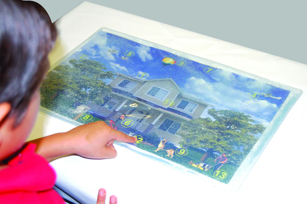 Child interacting with a digital or augmented reality display showing a house and garden.