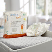 Package of McKesson training pants on a bed with a blurred background