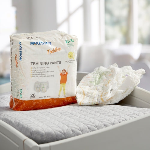 Package of McKesson training pants on a bed with a blurred background