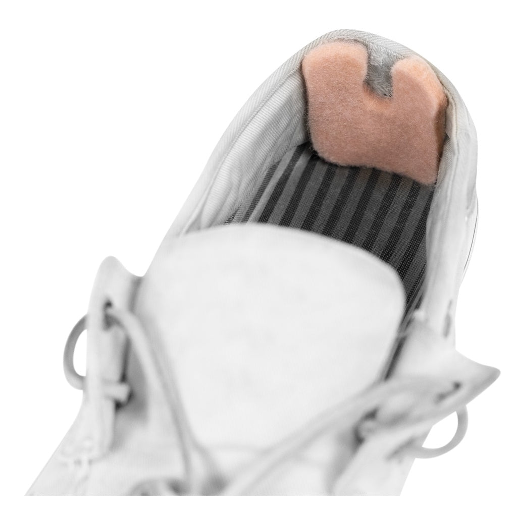 Close-up of a white sneaker with pink tongue and black lining on a white background