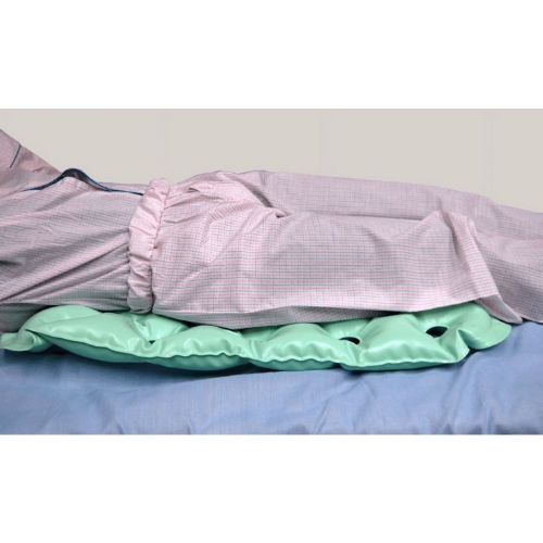 Bed with pink checkered sheets and a green pillow on a plain background