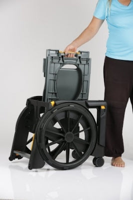 Person holding a black and gray portable toilet with wheels on a white background