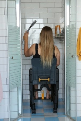 Person using a shower chair in a tiled bathroom