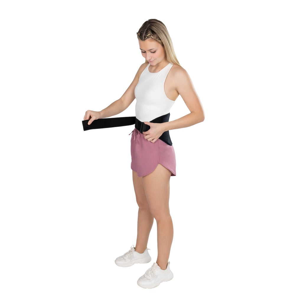 Woman holding a black waist trainer against her waist on a white background