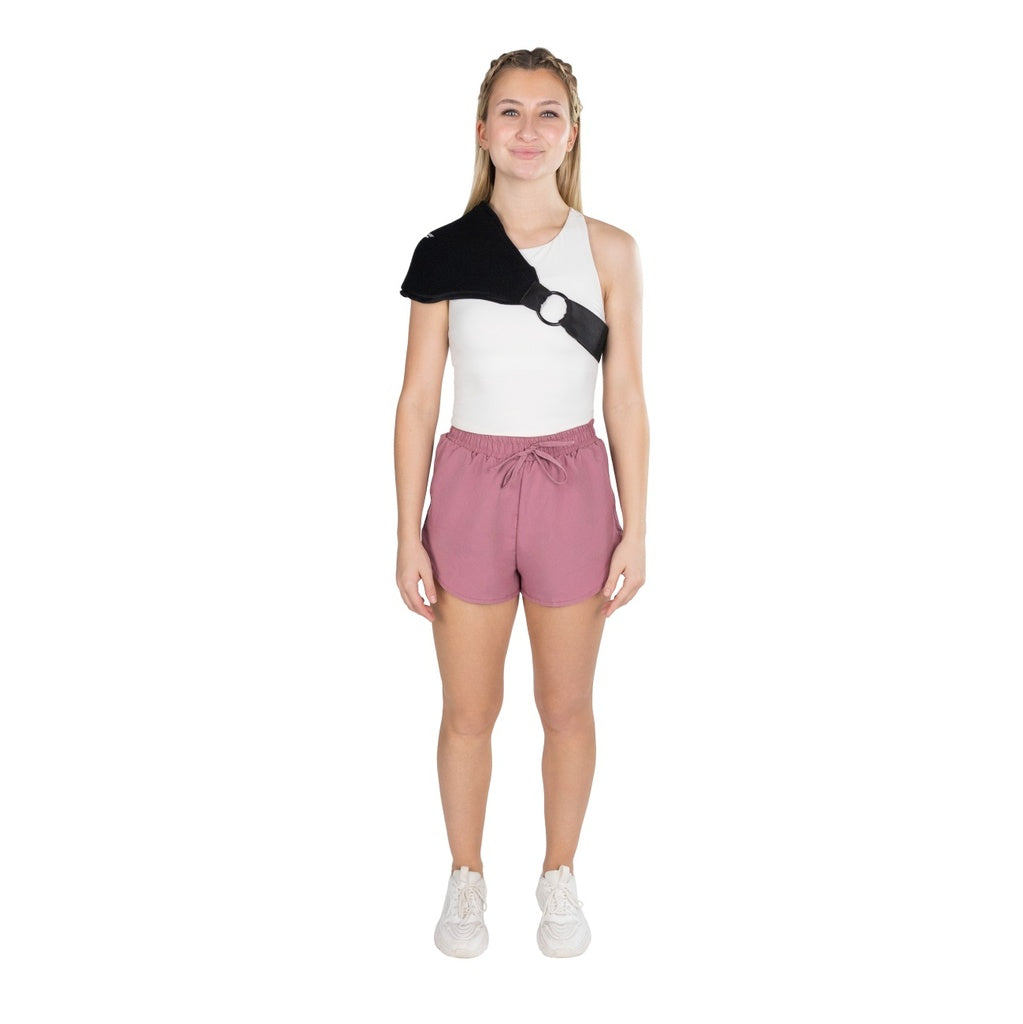Woman wearing a sleeveless black and white top with a large circle design and pink shorts on a white background