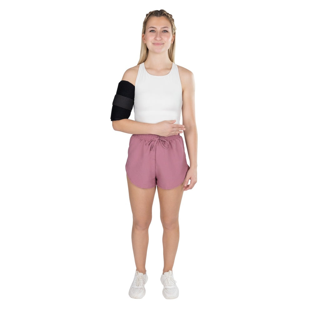 Woman wearing a white sleeveless top and pink shorts with a black arm brace on a white background